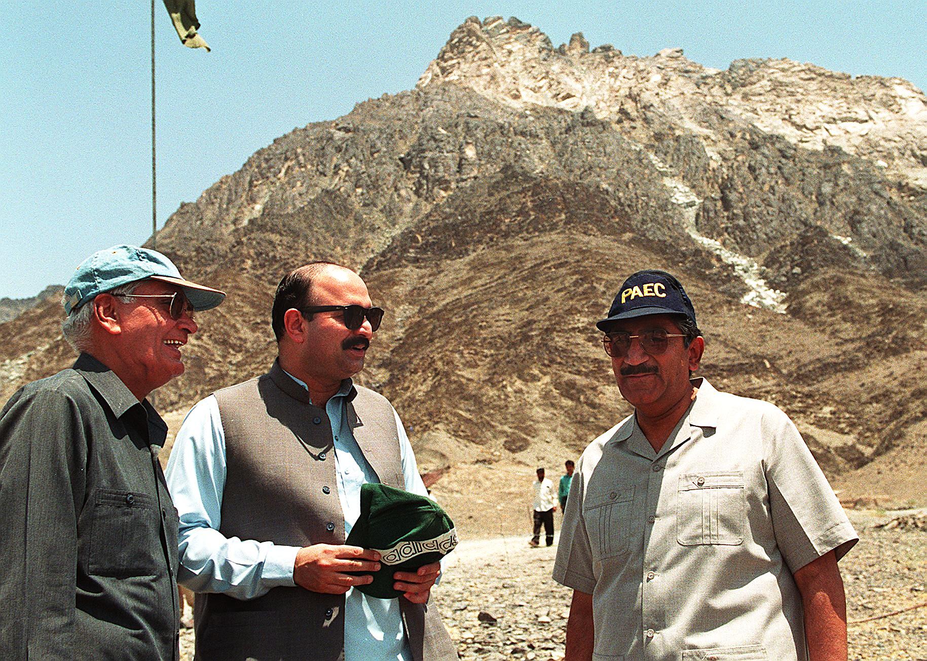 Pakistan's prominent scientists Dr. Samar Mubarak (R) and Dr. Ishfaq Ahmed (L), chairman of country's Atomic Energy Commission, stands in front of a hill under which Pakistan conducted its five nuclear tests, along with minister of information Mushahid Hussain, 29 June. Pakistan tested its six nuclear devices on 28 and 30 May simultaneously in Chaghi district of southwestern Baluchistan province. AFP PHOTO/ Saeed KHAN / AFP PHOTO / SAEED KHAN